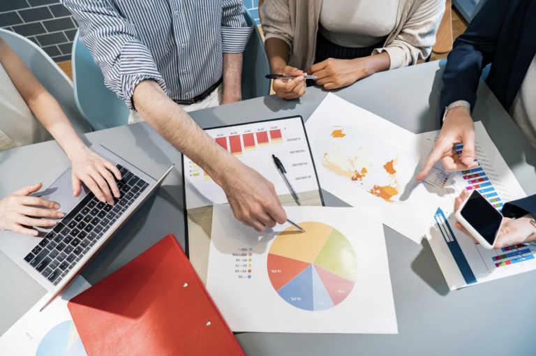 Team of professionals collaborating on charts and digital reports during a business strategy meeting
